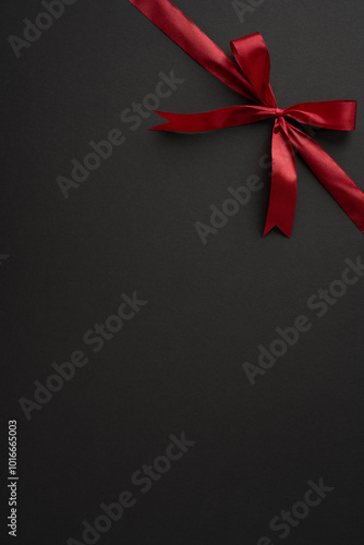 A stylish vertical red ribbon tied neatly into a bow against a dark backdrop. Perfect for themes of elegance, celebration, and gift wrapping