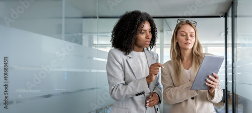 Two businesswoman working together using digital work tablet pc business project. Small creative diversity team of African American female and young woman do meeting in office. Banner, copy space