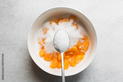 A tablespoon of white sugar, top view of granulated sugar in a silver measuring spoon