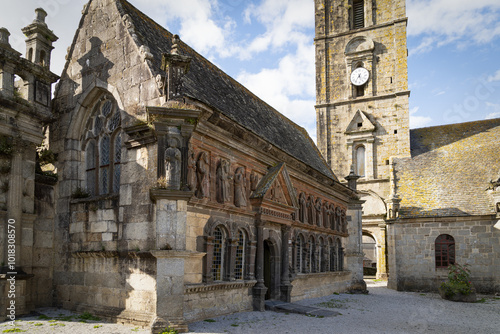 L'ossuaire de l'enclos paroissial de Sizun, construit en pierre, reflète l'architecture bretonne traditionnelle. Situé près de l'arc de triomphe, il s'impose sous un beau ciel d'été.