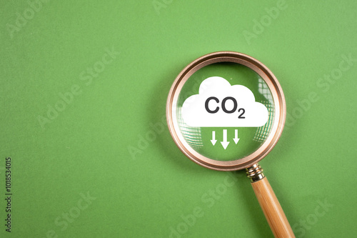 Hand holding CO2 reducing icon inside magnifier glass for focusing decrease CO2 or carbon dioxide emission ,carbon footprint and carbon credit to limit global warming from climate change concept..