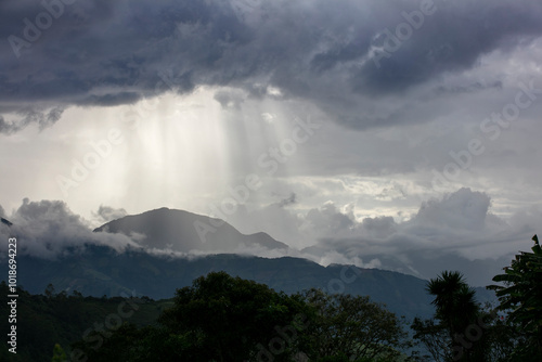 Golpe de luz en medio de nubes oscuras que golpean a una montaña en el horizonte