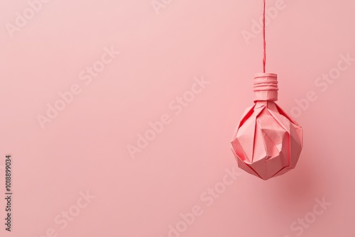 Creative minimalistic origami light bulb on pastel pink background closeup