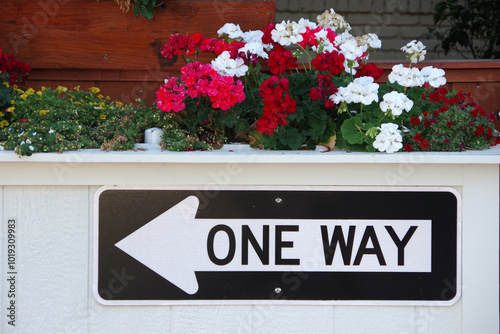 ONE WAY left sign on an urban white outdoor street barricade flower planter