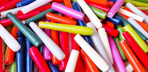 Background of multi-colored long burnt paraffin candles. Panorama.