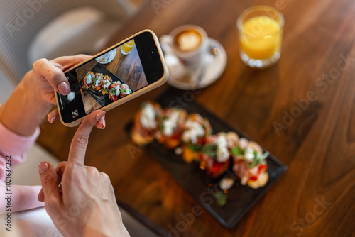 Woman influencer taking pictures of food in a restaurant. Social media. Food and drink concept.