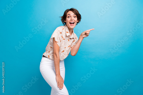 Photo of astonished cheerful lady indicate finger empty space unexpected news isolated on blue color background