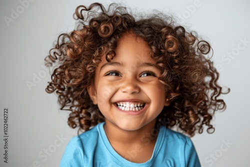 professional portrait of cute mixed race girl child model laughing and smiling with curly hair wearing blue shirt isolated on white background for advertisement and web design