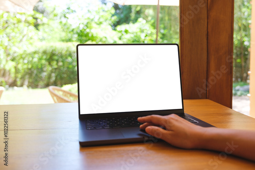 Mockup image of a woman using and touching on laptop computer with blank white desktop screen on wooden table