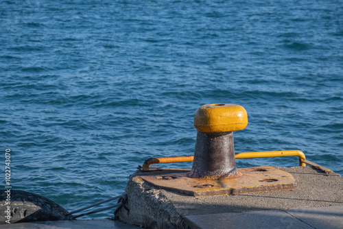 yellow rusty bollard on the quay. passenger ferry pier. sea in the background.