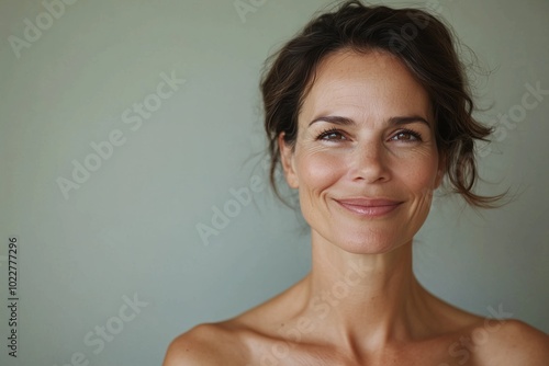 A warm portrait of a smiling mature woman with bare shoulders against a soft background