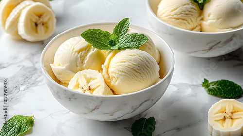 A marble countertop houses a bowl of ice cream with sliced bananas and mint sprigs, alongside a separate bowl of sliced bananas and mint