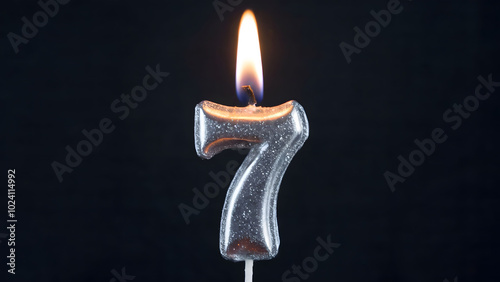 Shimmering Silver Number Seven Candle with a Lit Flame on a Dark Background, Symbolizing a Seventh Birthday or Special Occasion