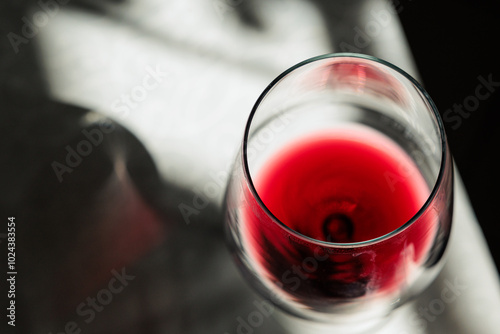 vista macro di un calice visto da sopra, riempito con del vino rosso ed appoggiato su un tavolo, illuminato dal sole