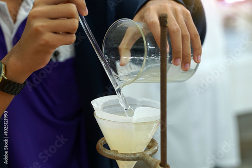 Experiment to separate mixed substances by pouring substances into a separator funnel through filter paper. Solid particles are placed on the filter paper. The liquid will flow into the beaker below.