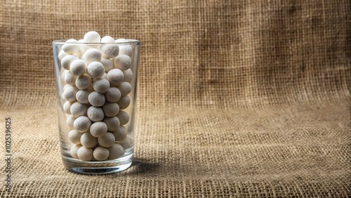 close up of moth balls in a glass jar on top of sackcloth