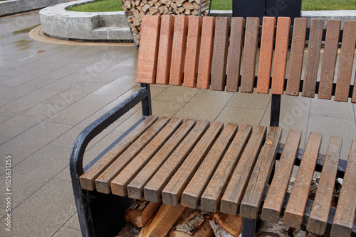 a wet brown wooden bench with metal armrests.