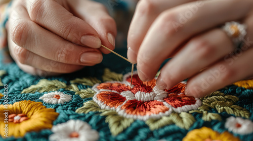 Hands embroidering colorful flowers on a textile background.