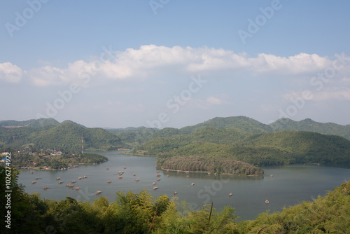 A raft floating on water in dam behind green mountain under cloudy sky location at north east of Thailand