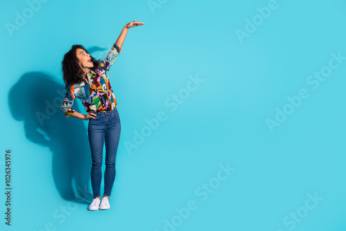 Photo of cheerful excited cute woman wear trendy clothes demonstrate empty space isolated on blue color background