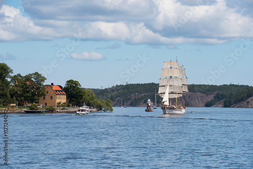 A sail boat brig and a lighthouse and commuting boats in the background heading for the Stockholm archipelago at the old toll point Blockhusudden. Stockholm