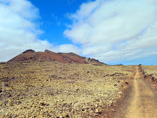 Volcanic landscape. Desert area with stones, rocks and sandstone and silhouette of volcano slopes on the horizon. Landscapes and extreme nature.