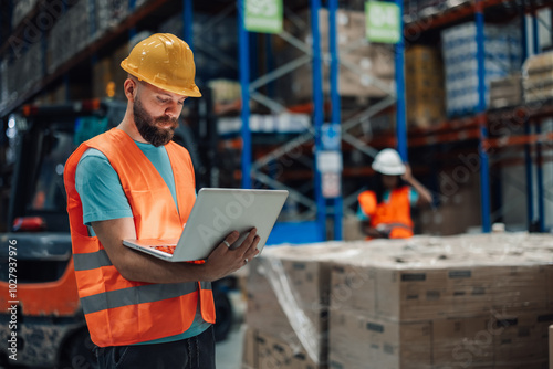 Warehouse worker using laptop checking inventory in logistics center