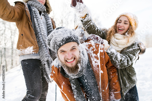 Friends in snowball fight in snowy nature, throwing snow and having fun. First snowfall of the season.