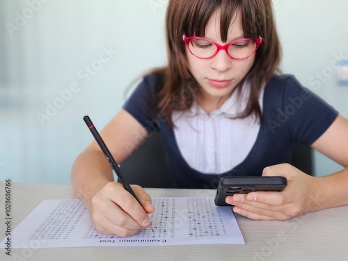 Student child holding smartphone during control exam test at school and cheating on the exam