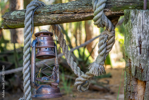 an old oil lamp hanging on a fence with a thick rope. wild west old farm equipment