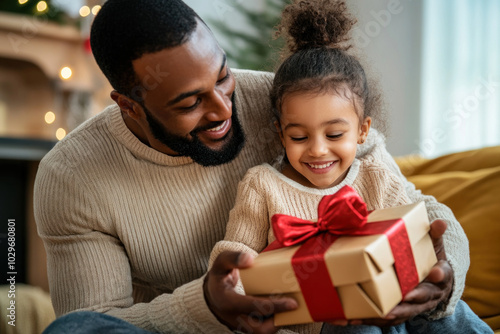 Father and daughter joyfully holding a present box.