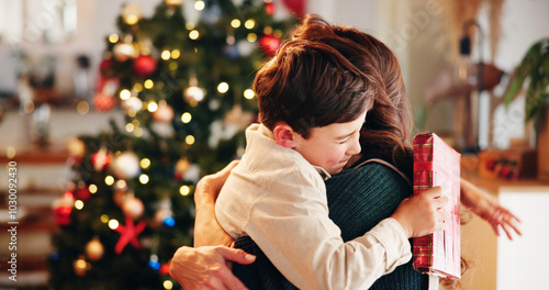 Christmas, gift and hug with mother, son and bonding together with decoration, house and festive in lounge. Xmas tree, family and parent with boy, embrace and present with happiness, holiday and love