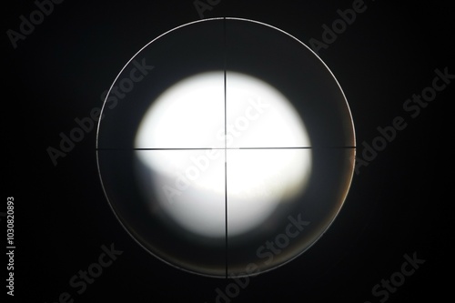 Optical lens with no target markings. Black and white photograph of an optical rifle lens with clear markings without a target. The sight is knocked off, blurry image in the lens.