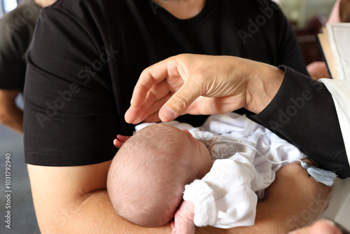 The priest baptizes the newborn in the church.