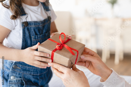 Closeup shot of mother giving receiving birthday Christmas New Year Mother`s day present gift box with red ribbon at home. Family celebration event