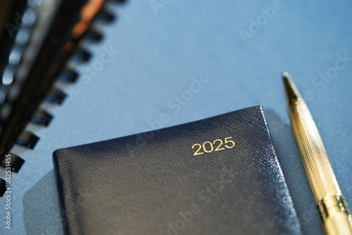 2025 with golden penn, blue diary on blue background