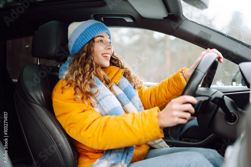 Happy woman in winter outfit driving car. The concept of transport, lifestyle.