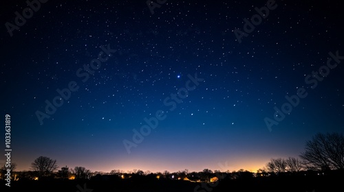 A serene night sky filled with stars, showcasing a tranquil landscape and distant lights.