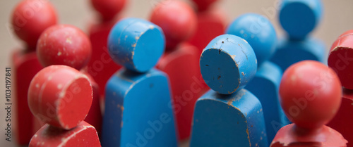 Painted red and blue wooden figures grouped together, symbolizing the divide between political parties or ideologies.