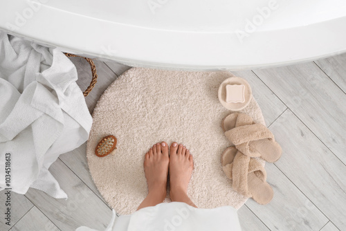 Barefoot woman on round mat in bathroom, top view