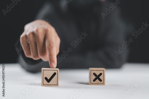 Businesswoman select correct sign mark between Cross mark which print screen on wooden cube block for approve and reject business proposal concept.