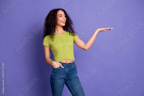 Photo portrait of attractive teen woman look hold empty space dressed stylish green clothes isolated on purple color background