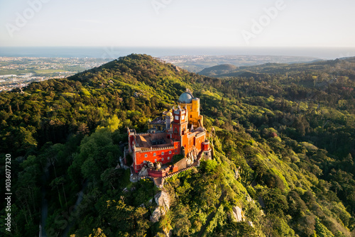 Aerial view of Pena Palace in Sintra, Portugal a Romanticist castle on hilltop surrounded by forest during sunset.