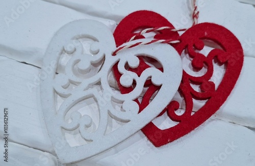 Red and white openwork heart on a background of a white brick wall