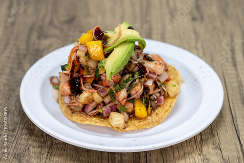 Delicious looking tostada exotica stacked high on a tortilla and topped with chopped fruit and avocado for an excellent Mexcian seafood meal