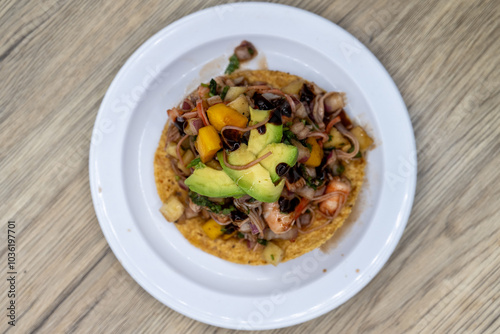 Overhead view of delicious looking tostada exotica stacked high on a tortilla and topped with chopped fruit and avocado for an excellent Mexcian seafood meal