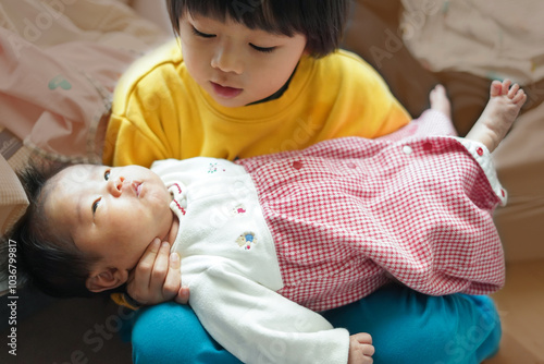 妹の首を支えて抱っこする男の子/A boy supporting his sister's neck and holding her in his arms