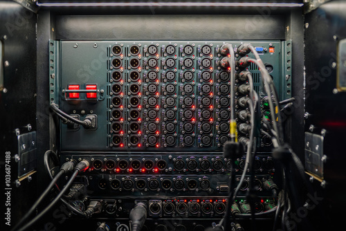 Close-up of a fully connected audio patch panel with numerous XLR ports and cables in a professional sound setup..