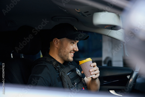 Portrait of smiling patrolman driving car drinking takeaway coffee