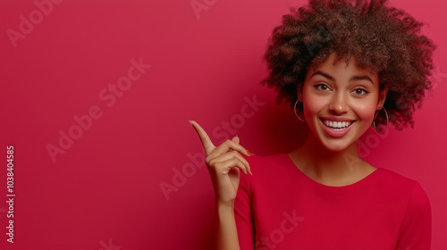 Kobieta o ciemnej karnacji z afro uśmiecha się do obiektywu. Wskazuje palcem w bok, sugerując miejsce na Twoją ofertę reklamową.